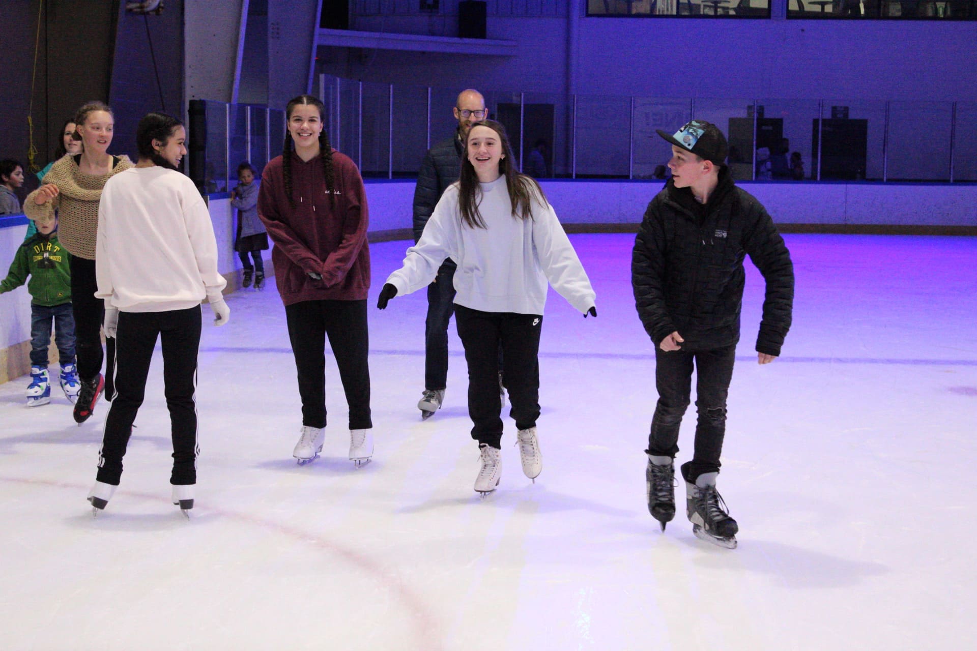 Group of friends ice skating together during evening open skate