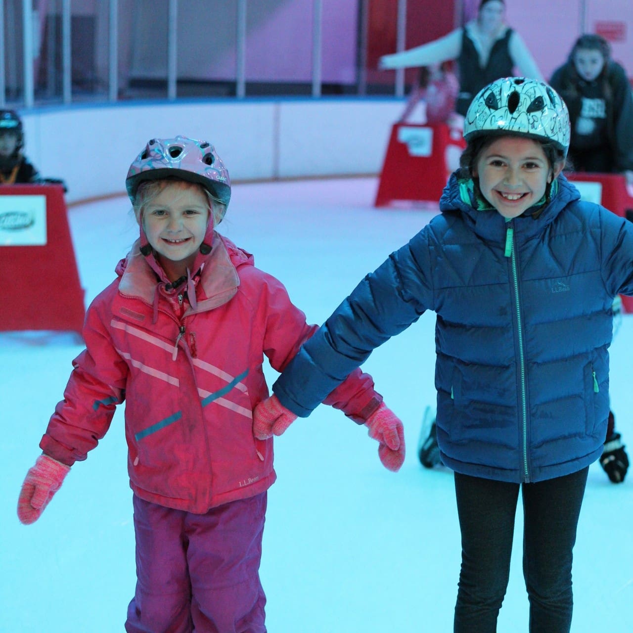 Young child wearing a helmet while learning to ice skate at the Iceplex